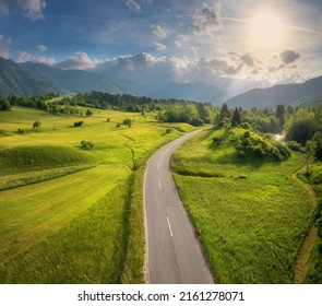 Aerial view of road in green meadows and hils at sunset in summer. Top view from drone of rural road, mountains, forest. Beautiful landscape with roadway, trees, green grass, sky with clouds. Slovenia - Powered by Shutterstock