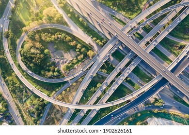 Aerial View Of Road Interchange Or Highway Intersection With Busy Urban Traffic Speeding On The Road. Junction Network Of Transportation Taken By Drone.