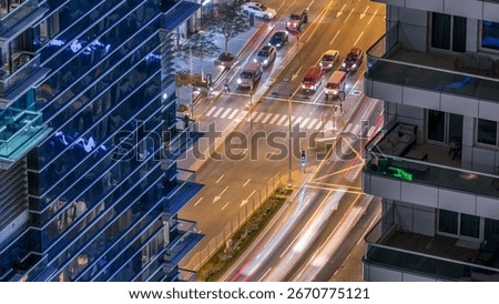 Aerial view of a road intersection in a big city between two skyscrapers night timelapse. Urban landscape of Dubai Marina and JBR district in UAE with cars