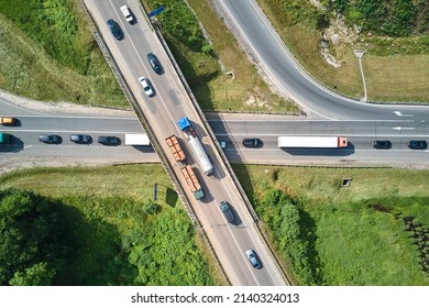 Aerial view of road intersection with fast moving heavy traffic on city streets. Uban transportation during rush hour with many cars and trucks