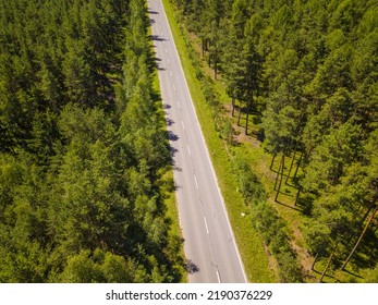 Aerial View Of Road Leading Through The Forest. Empty Highway In The Large Forest From Above. Environmental Concept Background.