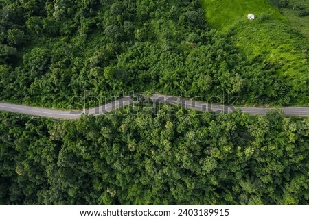 Aerial view of a road in the middle of the forest and road curve construction up to mountain.