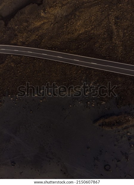 aerial view of road in the middle of volcanic\
nature. Game of geometries with neutral colors. Paradise Canary\
islands in Spain.