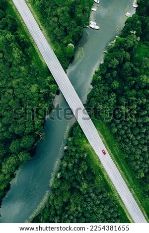 Aerial view of road over the blue river and green woods in summer Finland