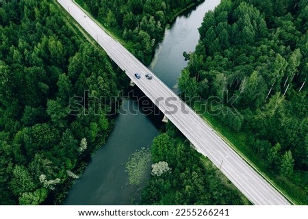 Aerial view of road over the blue river and green woods in summer Finland