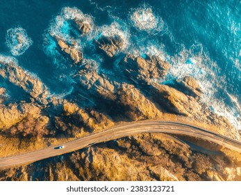 Aerial view of road, rocky sea shore with waves and stones at sunset in Lofoten Islands, Norway. Landscape with beautiful road, transparent blue water, rocks. Top drone view of highway in summer - Powered by Shutterstock