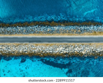 Aerial view of road, sea, stones at sunset in Lofoten Islands, Norway. Landscape with beautiful bridge, transparent blue water, rocks. Top down view from drone of highway in summer. Travel. Scenery - Powered by Shutterstock