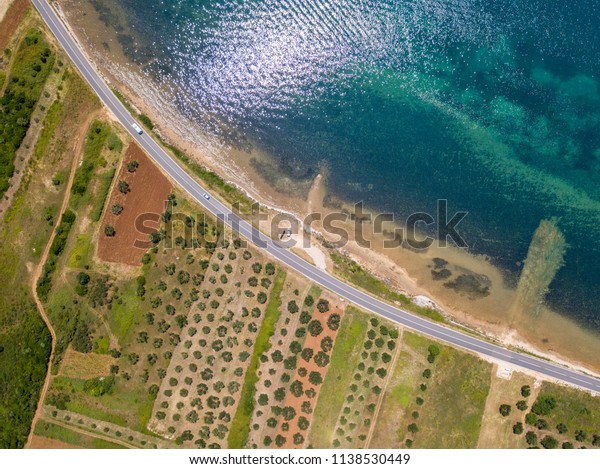 Aerial\
view of a road that runs along the Croatian coast and passes\
through agricultural fields, with plantations and cultivated\
fields. Road that runs along the sea. Coast\
line.