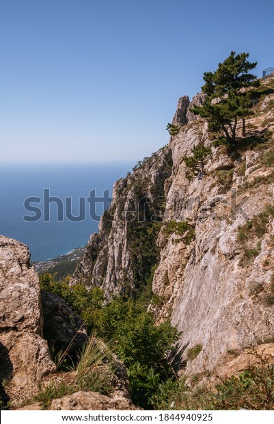 Aerial view of rock with a rope bridge on the\
Mount Ai-Petri in Crimea. Ai-Petri is one of the highest mountains\
in Crimea and tourist attraction. Hanging bridge on Ai-Petri over\
the abyss.