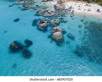 Aerial view of rocks on the sea. Overview of seabed seen from above, transparent water. Swimmers, bathers floating on the water. - Shutterstock ID 685907020