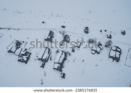 Aerial view of the roofs of village houses in winter,
the street with wooden dwellings is covered with snow. Map from the air
