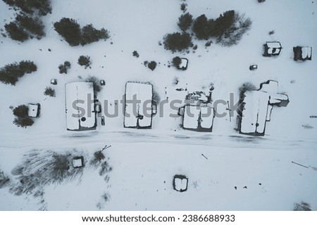 Aerial view of the roofs of village houses in winter,
the street with wooden dwellings is covered with snow. Map from the air