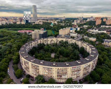 Aerial view of a round house in Moscow, skyscrapers in the background, summer nature in the frame. Aerial photography