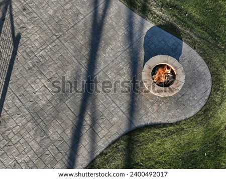 aerial view of round stone fire pit on stamped concrete patio in grass yard
