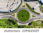 Aerial view of a roundabout with a large green flowerbed and cars moving in a circle