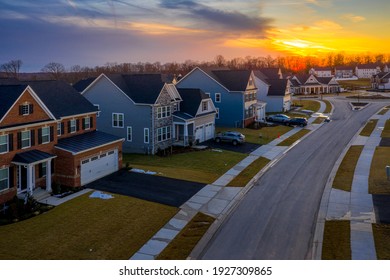 Aerial View Of A Row Of Multi Story Single Family Homes Real Estate Properties In A New Residential Suburban Neighborhood Street In Maryland USA With Dramatic Colorful Sunset Sky