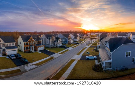 Aerial view of a row of multi story single family homes real estate properties in a new residential suburban neighborhood street in Maryland USA with dramatic colorful sunset sky