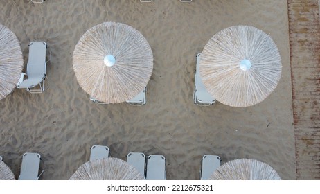 Aerial View Of Rows Of Cane Umbrellas And Sunbeds On A Sandy Mediterranean Beach