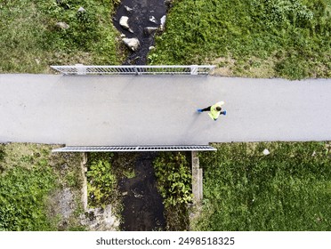 Aerial view of a runner running across bridge in park on a jogging path. Morning running training. - Powered by Shutterstock