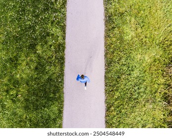 Aerial view of a runner running through the park on a jogging path. Morning running training. - Powered by Shutterstock