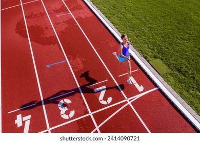 Aerial view of a running young female athlete on a tartan track crossing finishing line - Powered by Shutterstock