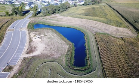 Aerial View Of Rural Blue Drainage Pond Surrounded By Farm Fields