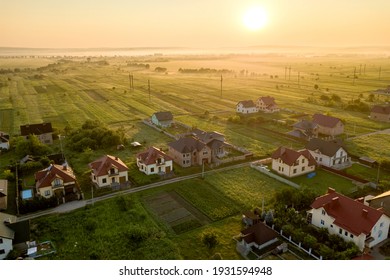 Aerial view of rural residential area with private homes between green fields at sunrise. - Powered by Shutterstock