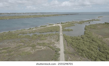 An aerial view of a rural road meandering through lush fields, surrounded by greenery. The scene offers a unique perspective of the open landscape, showcasing the harmony between nature and the road - Powered by Shutterstock