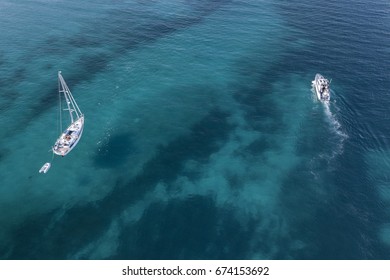 Aerial View Of A Sail Boat And Yachts On Amazing Beach With A Turquoise And Transparent Sea. Emerald Coast, Sardinia, Italy...