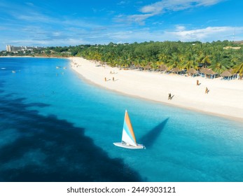 Aerial view of the sailboat on blue sea, white sandy beach at sunset. Summer vacation in Kendwa, Zanzibar. Tropical landscape with boat, yacht, ocean with clear water, green palms, sky. Top drone view - Powered by Shutterstock