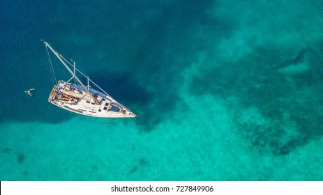 Aerial view of sailing boat anchoring on coral reef. Bird eye view, water sport theme.