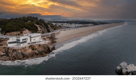 Aerial view of San Francisco's coastline featuring Cliff House on rocky outcrop, Ocean Beach, urban landscape, and distant hills under an overcast sky. - Powered by Shutterstock