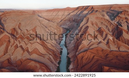 An aerial view of the San Juan River winding through the desert landscape near Mexican Hat. The juxtaposition of the river against the rugged Raplee Ridge forms a captivating tableau.