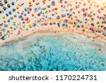 Aerial view of sandy beach with colorful umbrellas, swimming people in sea bay with transparent blue water at sunset in summer. Travel in Mallorca, Balearic islands, Spain. Top view. Landscape
