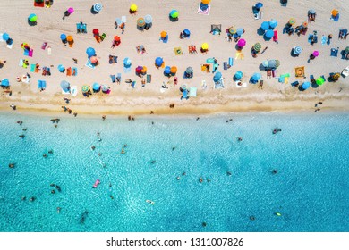 Aerial view of sandy beach with colorful umbrellas, swimming people in sea bay with transparent blue water at sunny day in summer. Travel in Mallorca, Balearic islands, Spain. Top view. Seascape