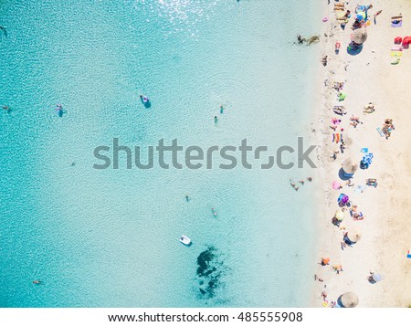 Aerial view of sandy beach with tourists swimming in beautiful clear sea water