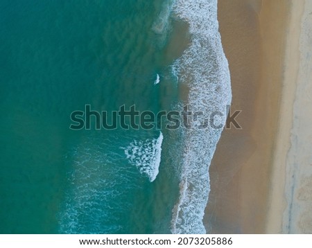 Luftaufnahme Panoramadrohne Blick auf den blauen Ozean Wellen, die am Sandstrand in Portugal erdrücken.