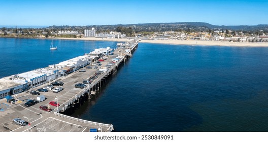 Aerial view of Santa Cruz, California, showcasing the Santa Cruz Wharf, Monterey Bay, sandy beach, and vibrant Beach Boardwalk under a clear sky. - Powered by Shutterstock