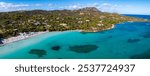 Aerial view of a Sardinian beach in Italy, featuring turquoise waters, sandy shoreline with sunbathers, beach umbrellas, and lush greenery along the coast.