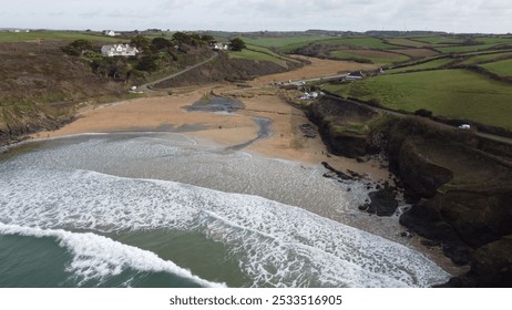 Aerial view of a scenic coastal landscape featuring a beach, cliffs, and green fields in the background. - Powered by Shutterstock