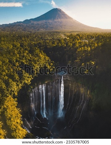 Aerial view of the scenic and incredible Tumpak Sewu waterfall at sunrise time with Semeru Volcano at the background - Pronojiwo, East Java - Indonesia