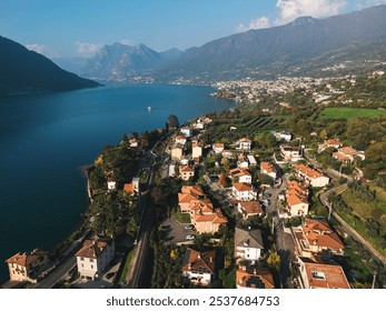 Aerial view of a scenic lakeside town surrounded by lush green hills and mountains, with red-roofed houses and a clear blue lake extending towards the horizon
 - Powered by Shutterstock