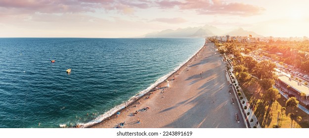 Aerial view of scenic and popular Konyaalti beach in Antalya resort town. Majestic mountains with haze in the background. Vacation and holiday in Turkiye - Shutterstock ID 2243891619