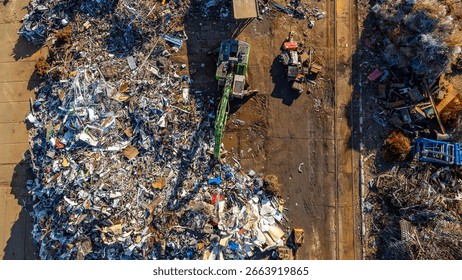 Aerial view of a scrapyard with a material handler sorting metal waste. Piles of scrap and industrial surroundings.
