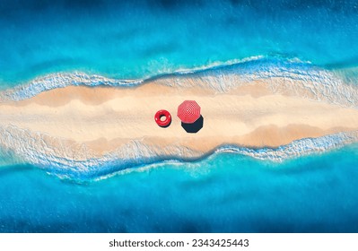 Aerial view of sea with waves on the both sides and sandy beach with colorful red umbrella and swim ring at sunset. Top view of sandbank. Summer travel. Tropical background with sand and blue ocean - Powered by Shutterstock