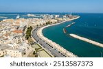 Aerial view of the seafront of Bari, Puglia, Italy. There is a road that runs along the sea and the city. The sea is clear despite the proximity of the city.