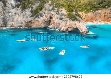 Aerial view of seascape with boats on blue sea in the morning at dawn in summer. Motorboats  with people on sea bay with rocks in clear blue water. Top view from drone. Travel holiday background