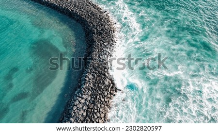 Aerial view of a seawall with clear turquoise water