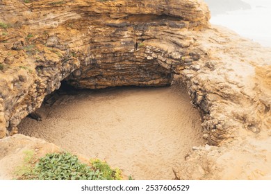 Aerial view of a secluded beach cove tucked away in a rocky cliff formation. The golden sand and dramatic rock formations create a stunning natural landscape. - Powered by Shutterstock