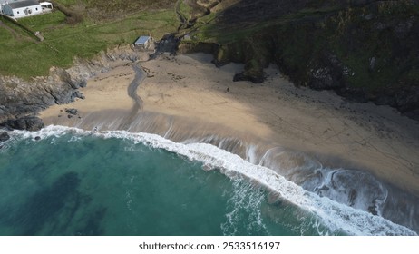 Aerial view of a secluded beach with turquoise waters and rocky cliffs, featuring a few houses on the grassy hilltop. - Powered by Shutterstock